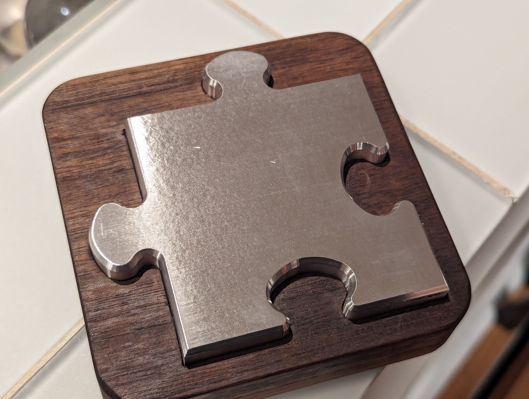 Puzzle piece of aluminium and walnut